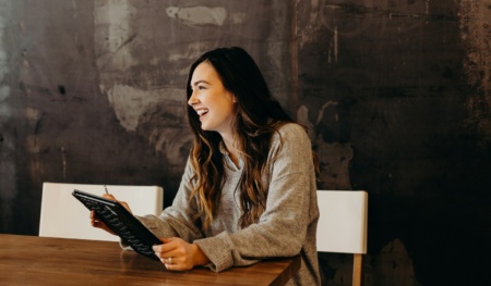 woman sitting around table holding tablet